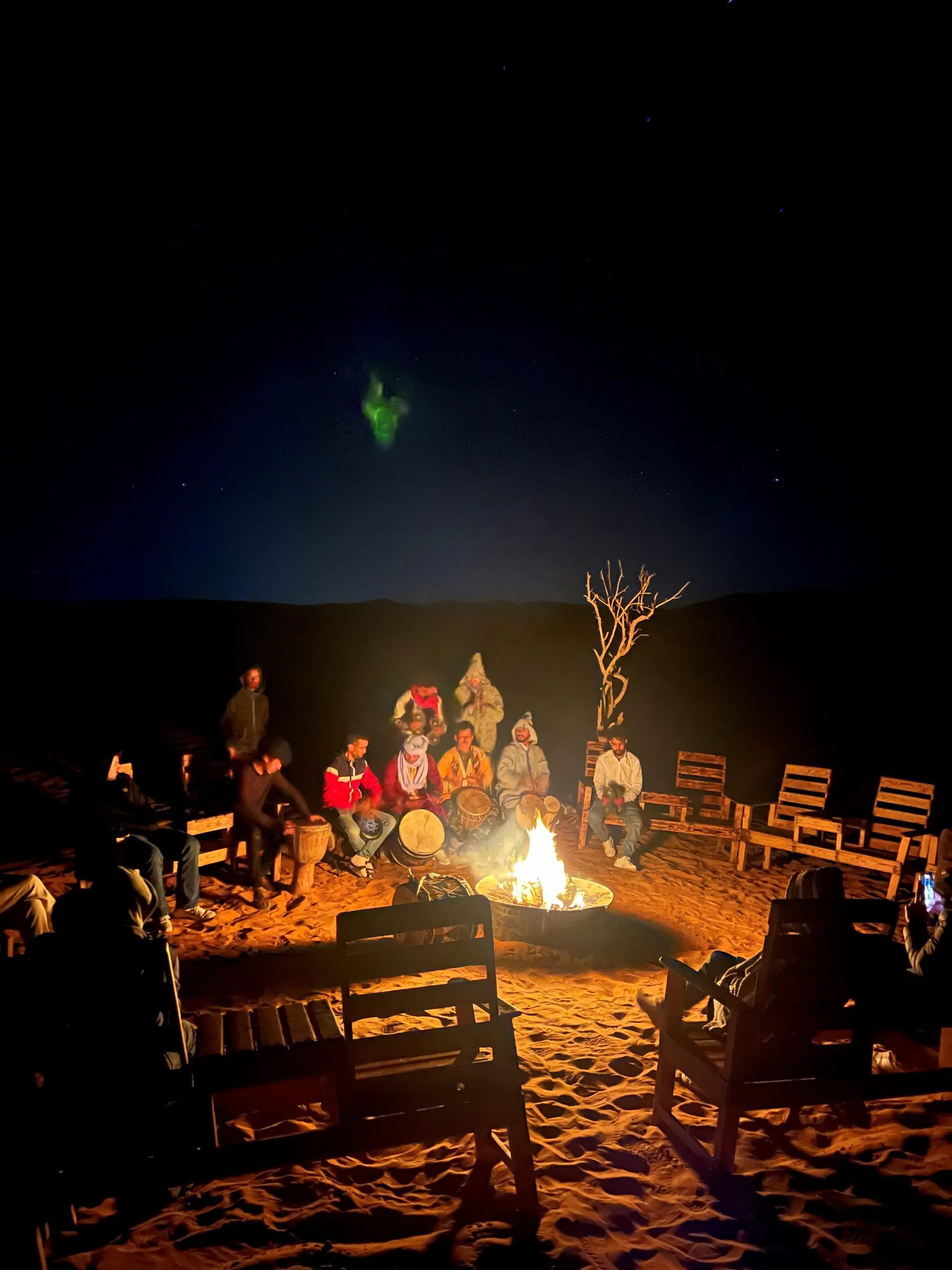 Guests gathered around a campfire at a Berber desert camp under the stars